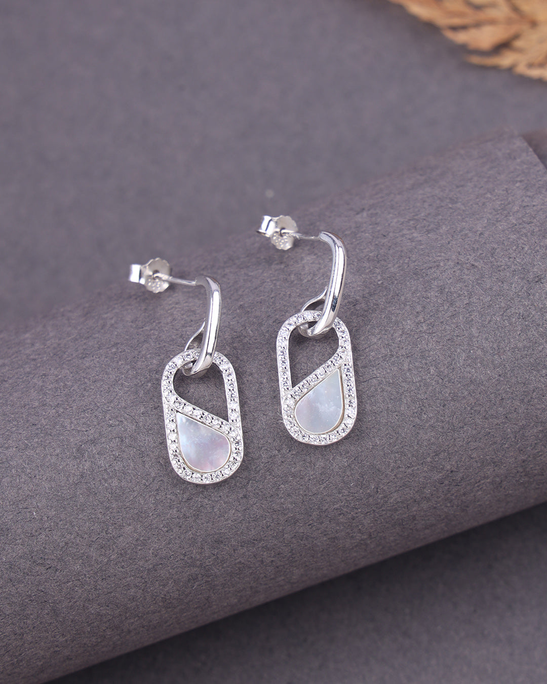 Silver earrings with MOP on a gray surface