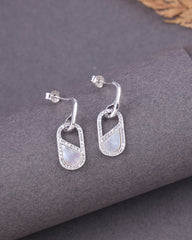 Silver earrings with MOP on a gray surface
