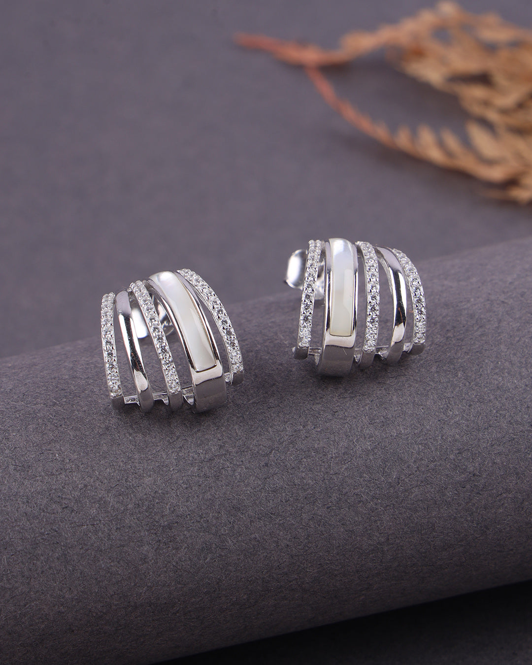 Silver earrings with a ribbed design on a dark surface