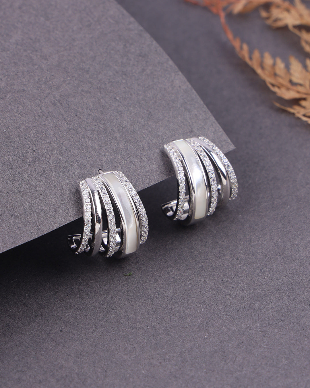 Silver hoop earrings on a gray surface with a blurred background
