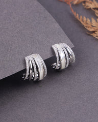 Silver hoop earrings on a gray surface with a blurred background