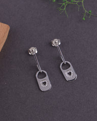 Pair of silver earrings with heart designs on a dark surface.