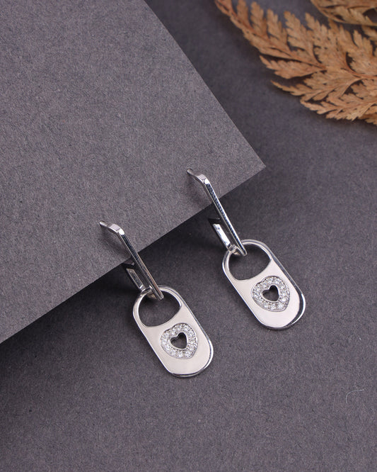 Silver earrings with heart designs on a gray surface
