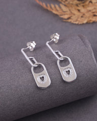 Silver earrings with heart designs on a gray surface