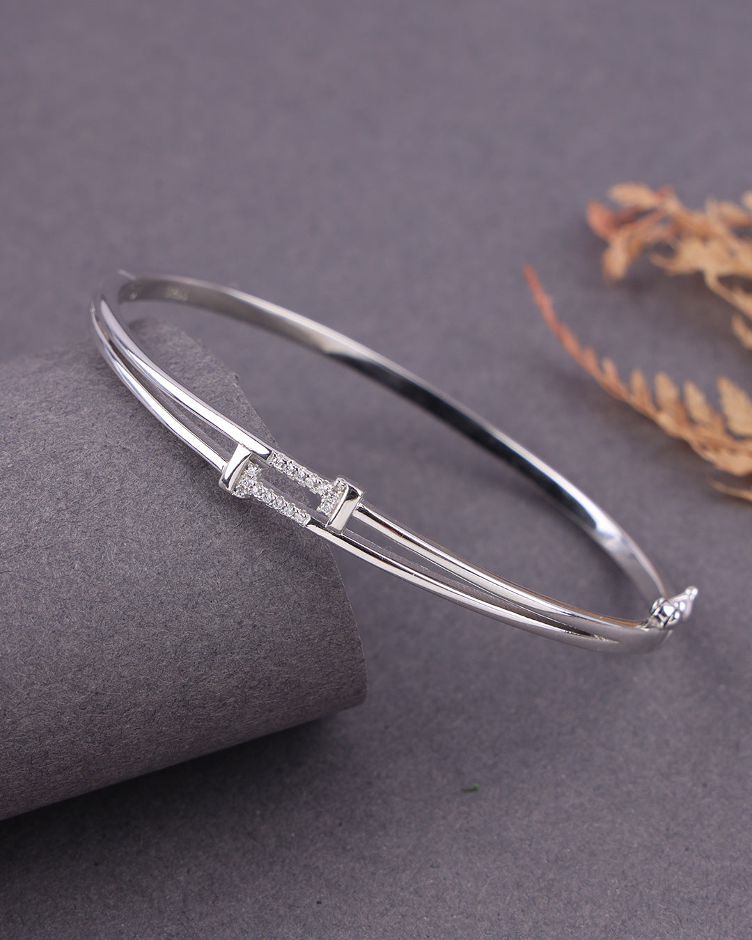Silver bracelet on a gray surface with a subtle background
