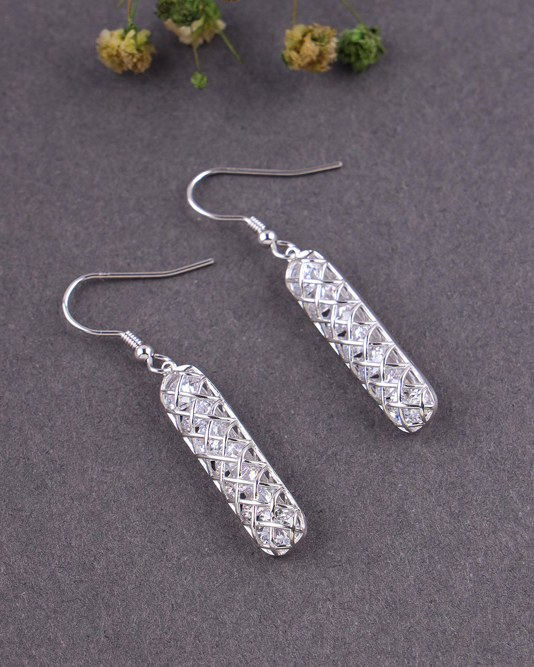 Silver earrings with geometric design on a gray background