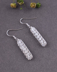 Silver earrings with geometric design on a gray background