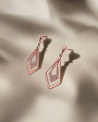 Rose gold earrings on a beige background