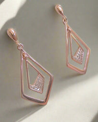 Rose gold earrings with diamond-like stones on a light background