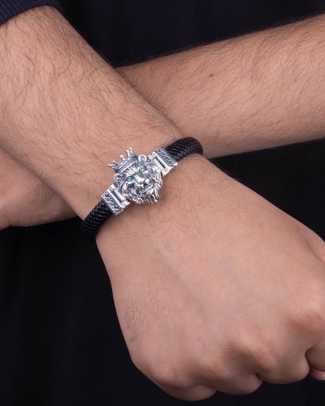 Silver bracelet with a lion head design on a wrist against a dark background