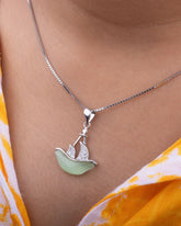 925 Sterling silver Necklace with a pendant shaped like a sailboat on a person wearing a yellow and white patterned garment.