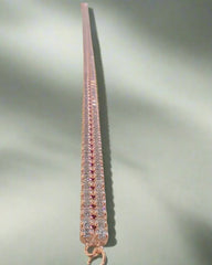 Rose gold bracelet with clear stones on a light gray background