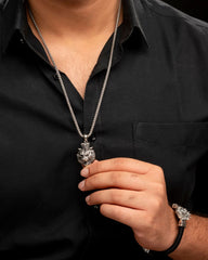Person wearing a black shirt with a silver necklace and bracelet on a dark background
