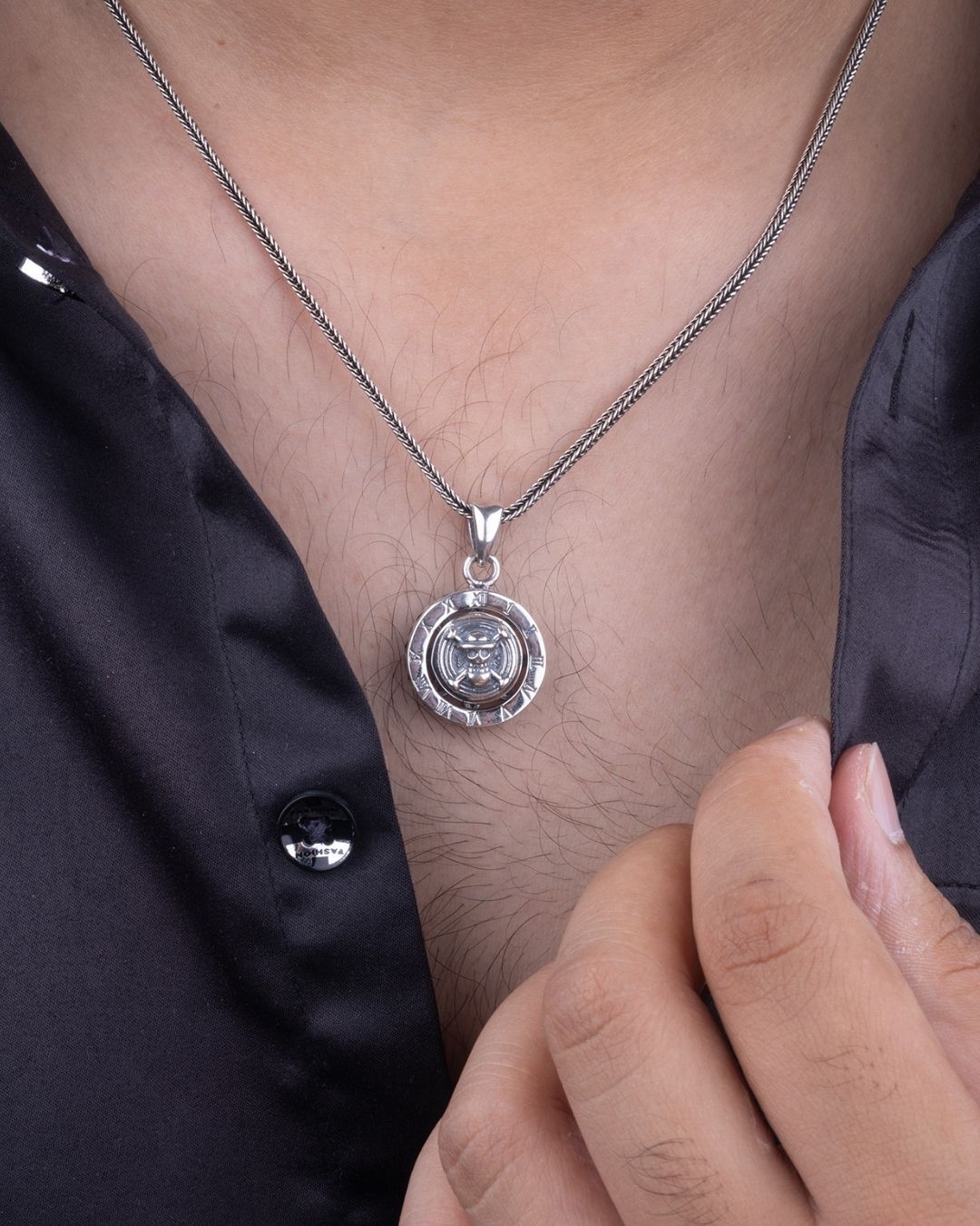 Silver necklace with a pendant on a person wearing a black shirt.
