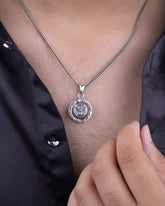 Silver necklace with a pendant on a person wearing a black shirt.
