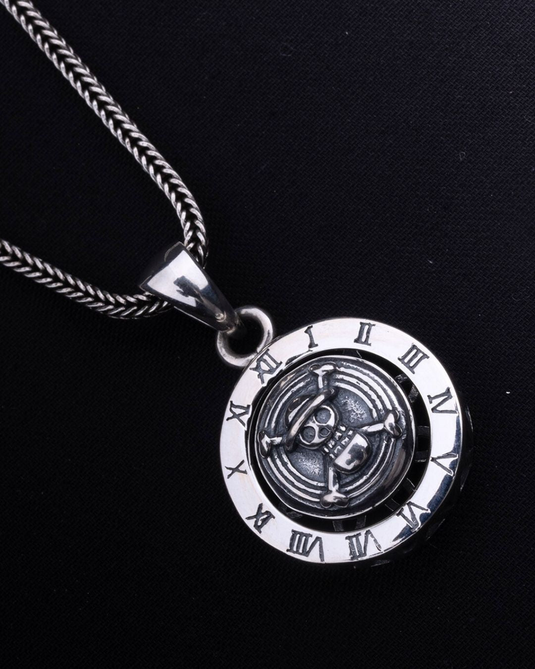 Silver pendant with Roman numeral design on a black background