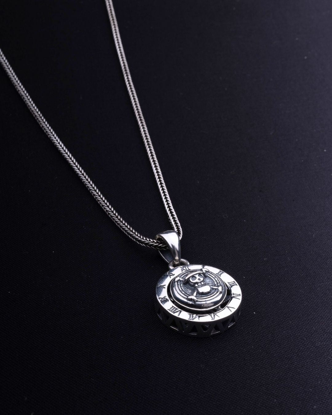 Silver necklace with a pendant on a black background