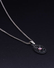 Necklace with a pendant featuring a pink stone on a black background