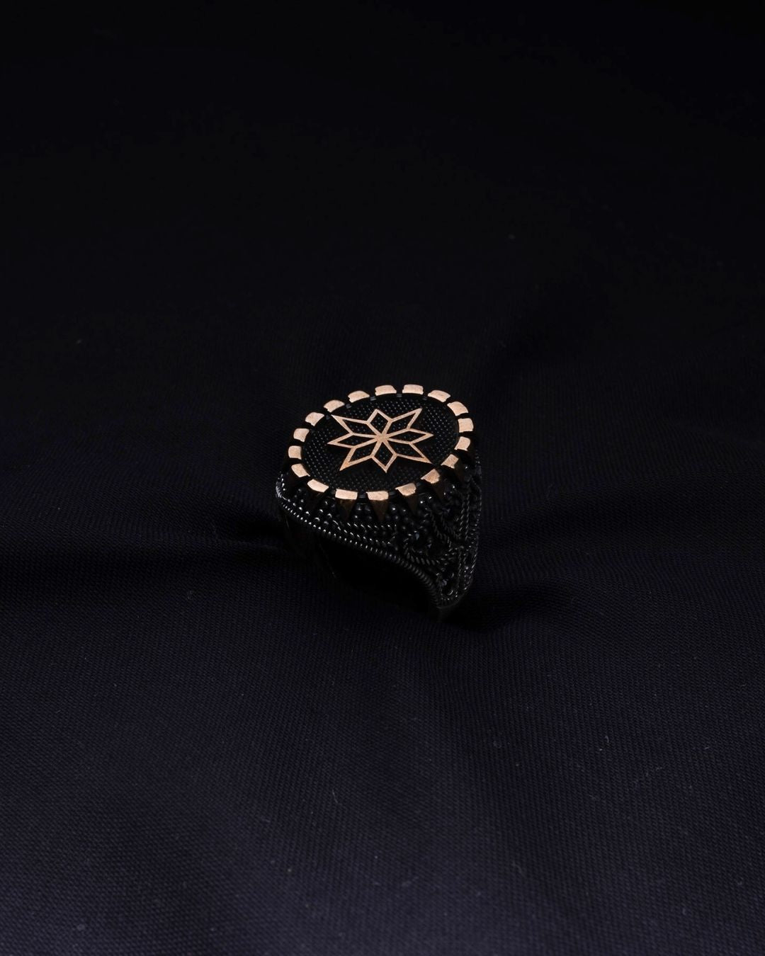 Black ring with gold star design on a black background