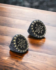 Two black and gold patterned objects on a wooden surface