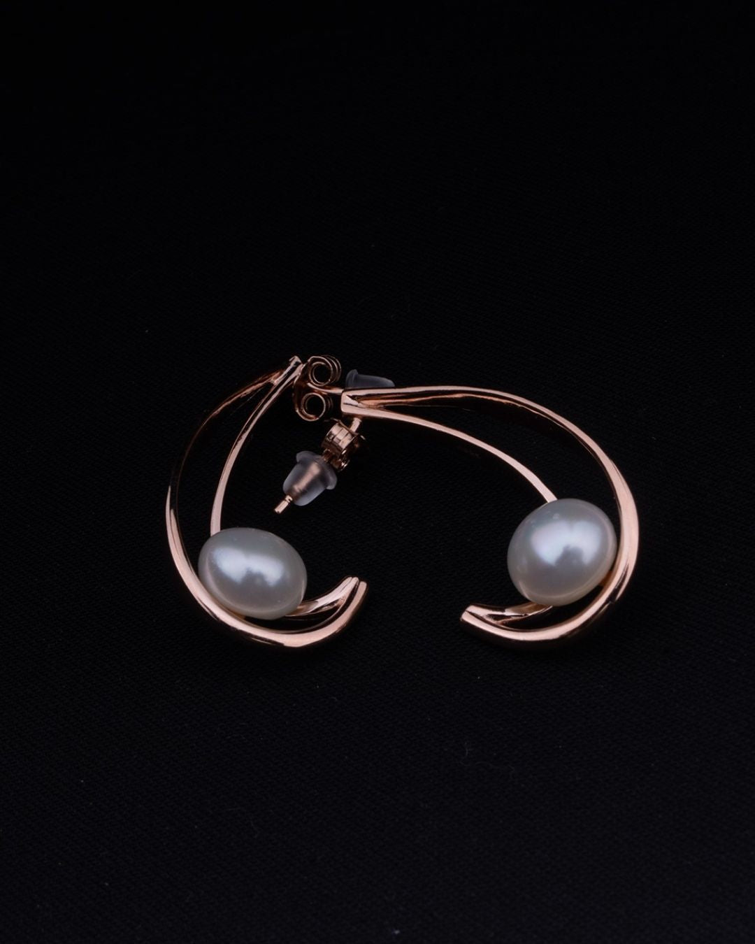 Rose gold bracelet with two pearls on a black background