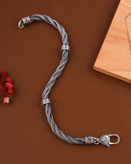 Silver braided bracelet with decorative clasp on a brown background
