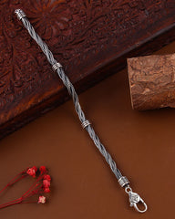 Silver braided bracelet with a clasp on a brown surface with wooden background