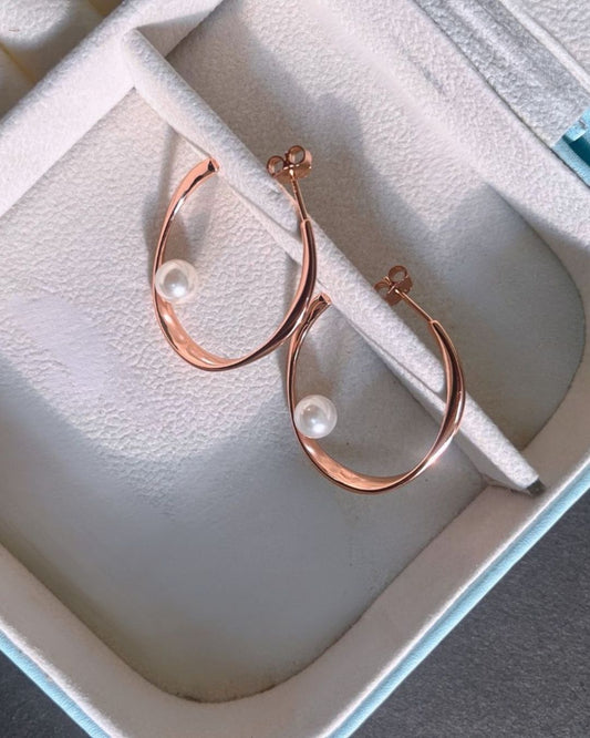 Rose gold hoop earrings with pearls on a white jewelry box