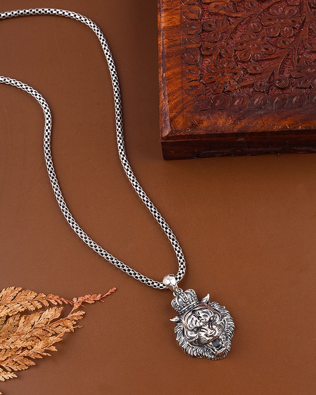 Silver necklace with a detailed pendant on a brown surface