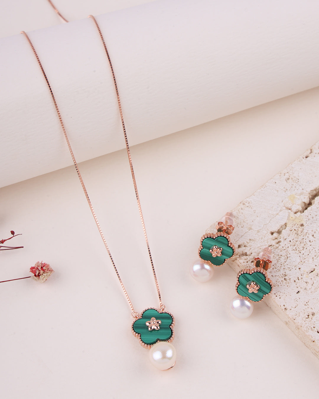 Jewelry set with green floral pendant necklace and earrings on a light background