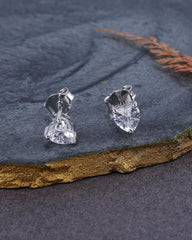 Pair of silver heart-shaped earrings on a dark stone surface