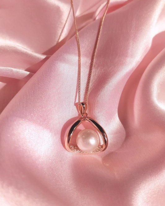Rose gold necklace with a pearl pendant on pink satin fabric