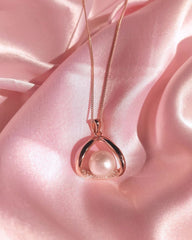 Rose gold necklace with a pearl pendant on pink satin fabric