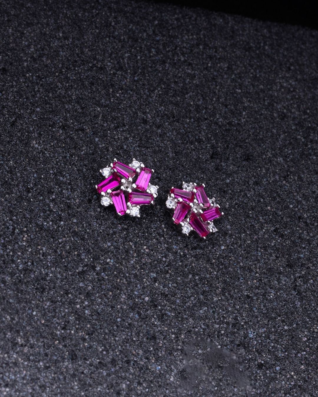 Pair of 925 Sterling silver earrings with pink gemstones on a dark textured background