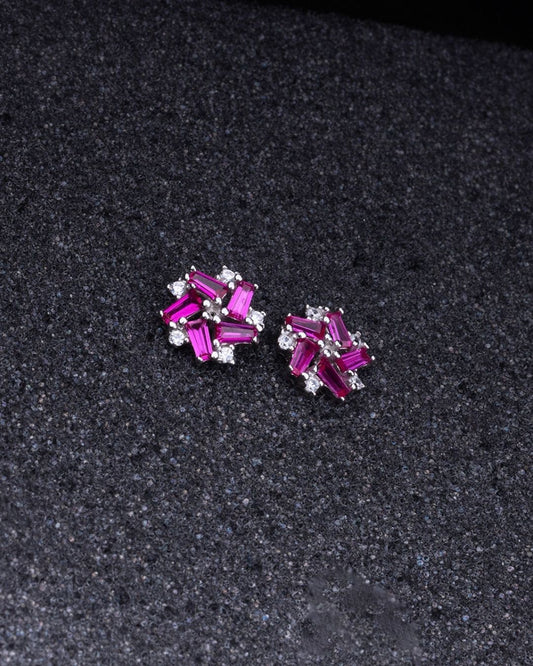 Pair of 925 Sterling silver earrings with pink gemstones on a dark textured background