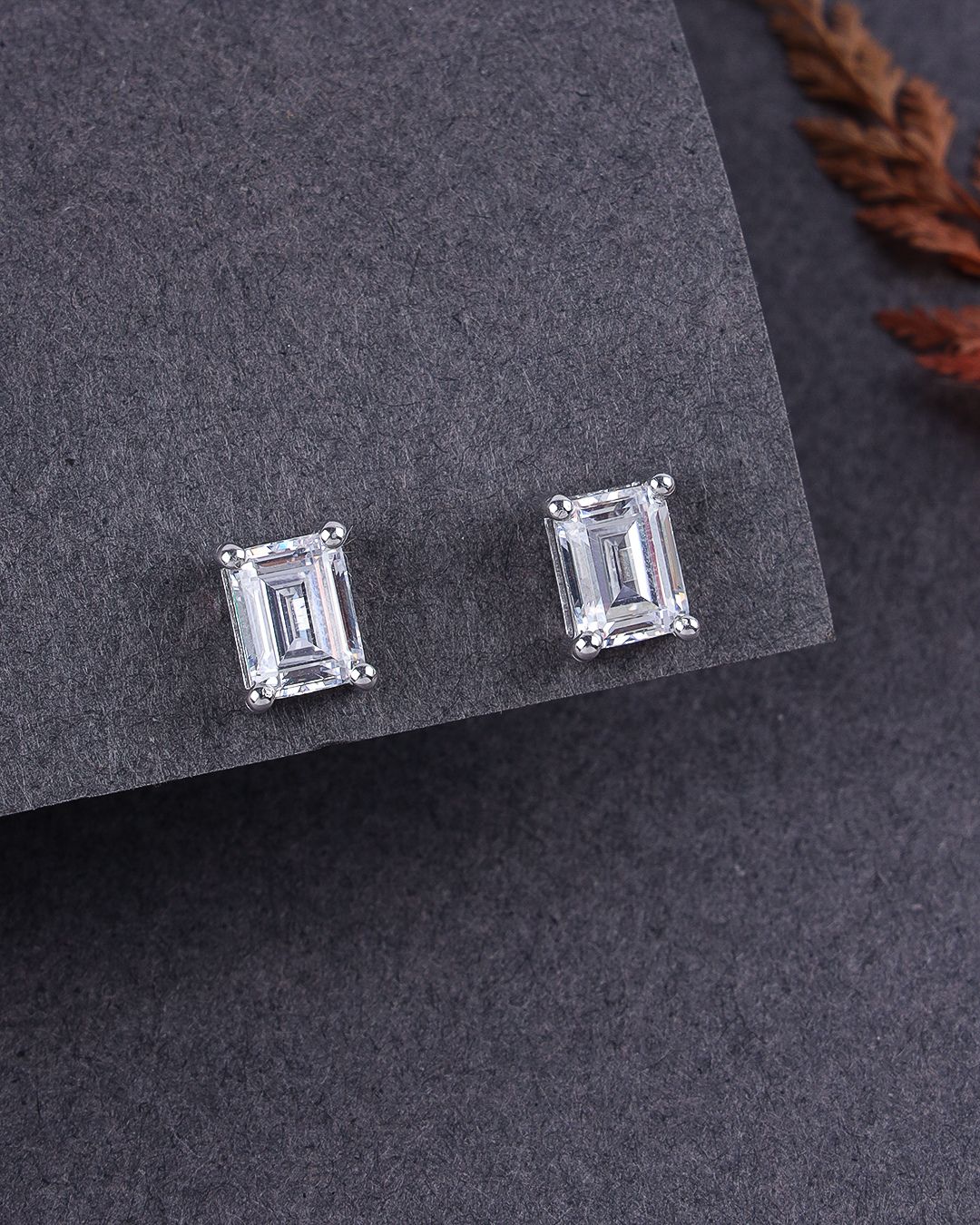 Pair of emerald-cut stud earrings on a gray surface