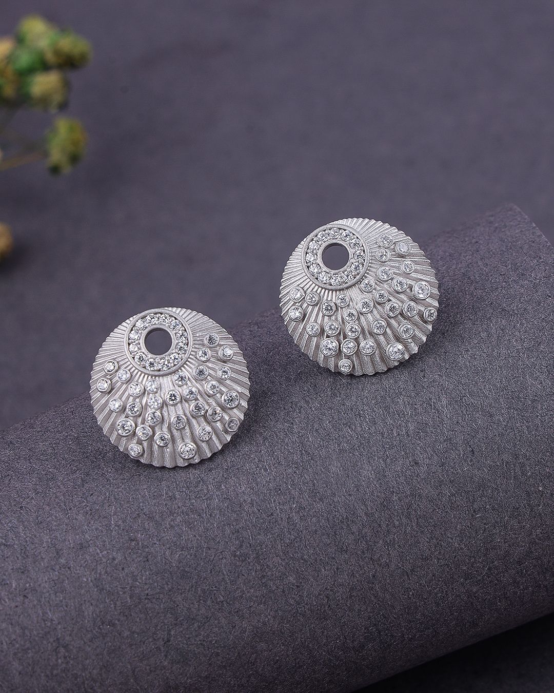 Pair of silver earrings on a textured gray surface with a blurred background