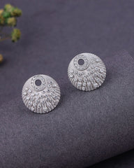 Pair of silver earrings on a textured gray surface with a blurred background