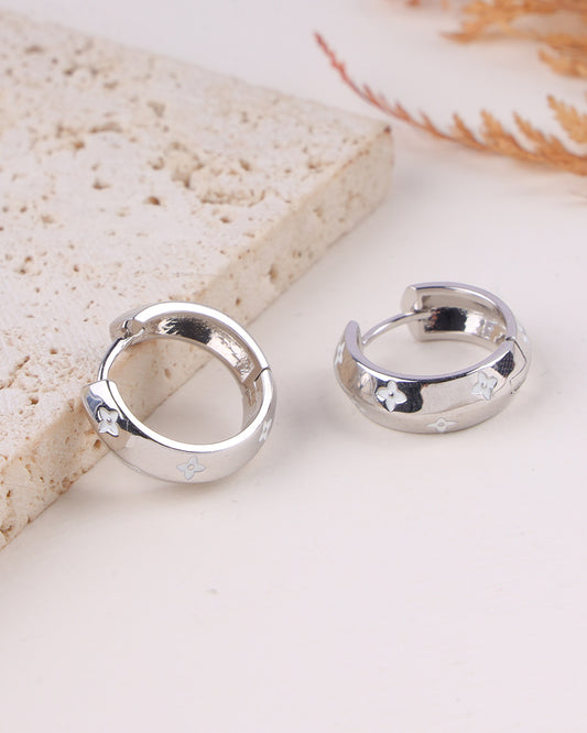 Silver hoop earrings on a light stone surface
