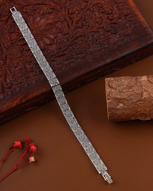 Silver bracelet on a brown textured surface with a wooden box in the background