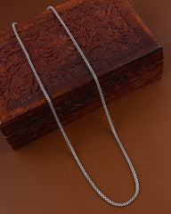 Silver chain on a wooden box with intricate carvings on a brown background