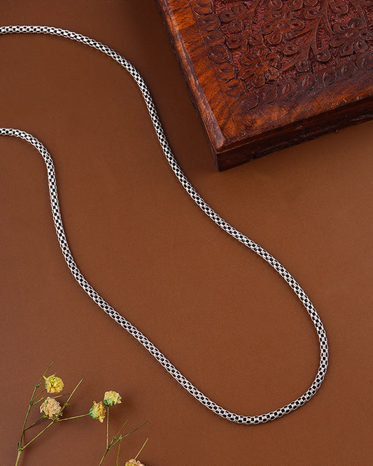 Black and white patterned rope on a brown surface with a wooden block and dried flowers.