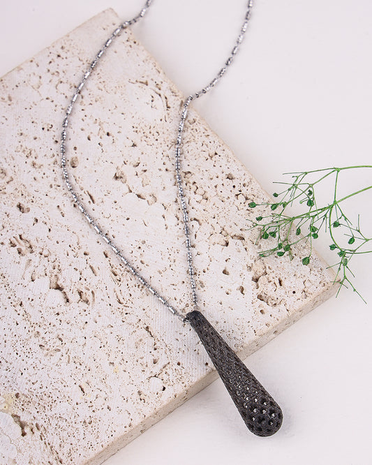 Necklace with a textured pendant on a stone surface