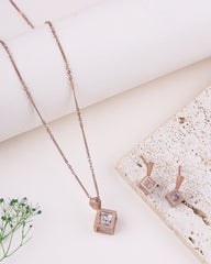 Rose gold necklace and earrings on a textured surface with a light background