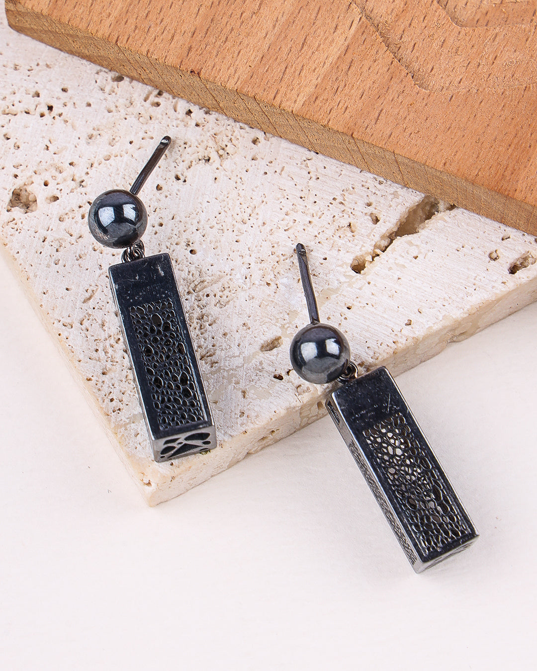 Black rhodium silver earrings with spherical beads on a stone surface