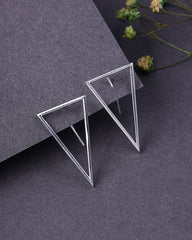 Silver triangle earrings on a dark gray surface with dried flowers.