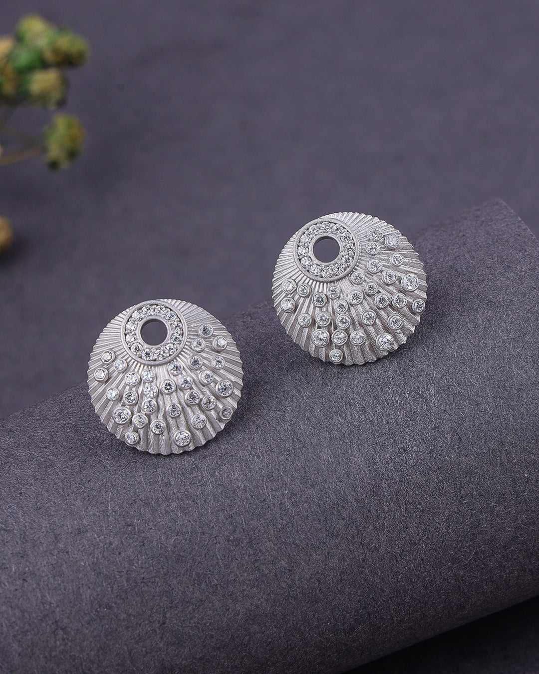 Pair of silver earrings on a dark textured surface with a blurred background