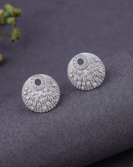 Pair of silver earrings on a dark textured surface with a blurred background