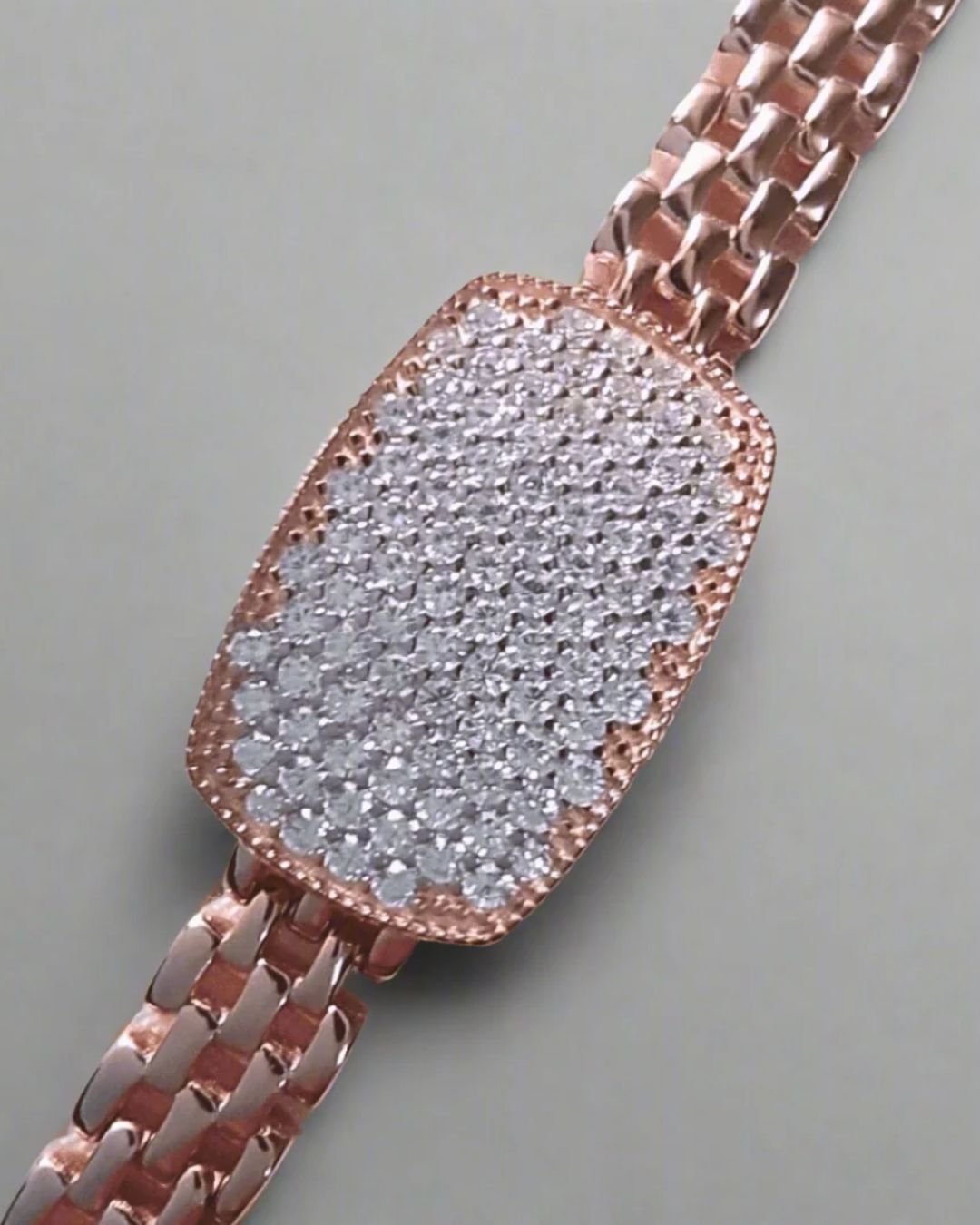 Rose gold watch with a diamond-studded face on a gray background