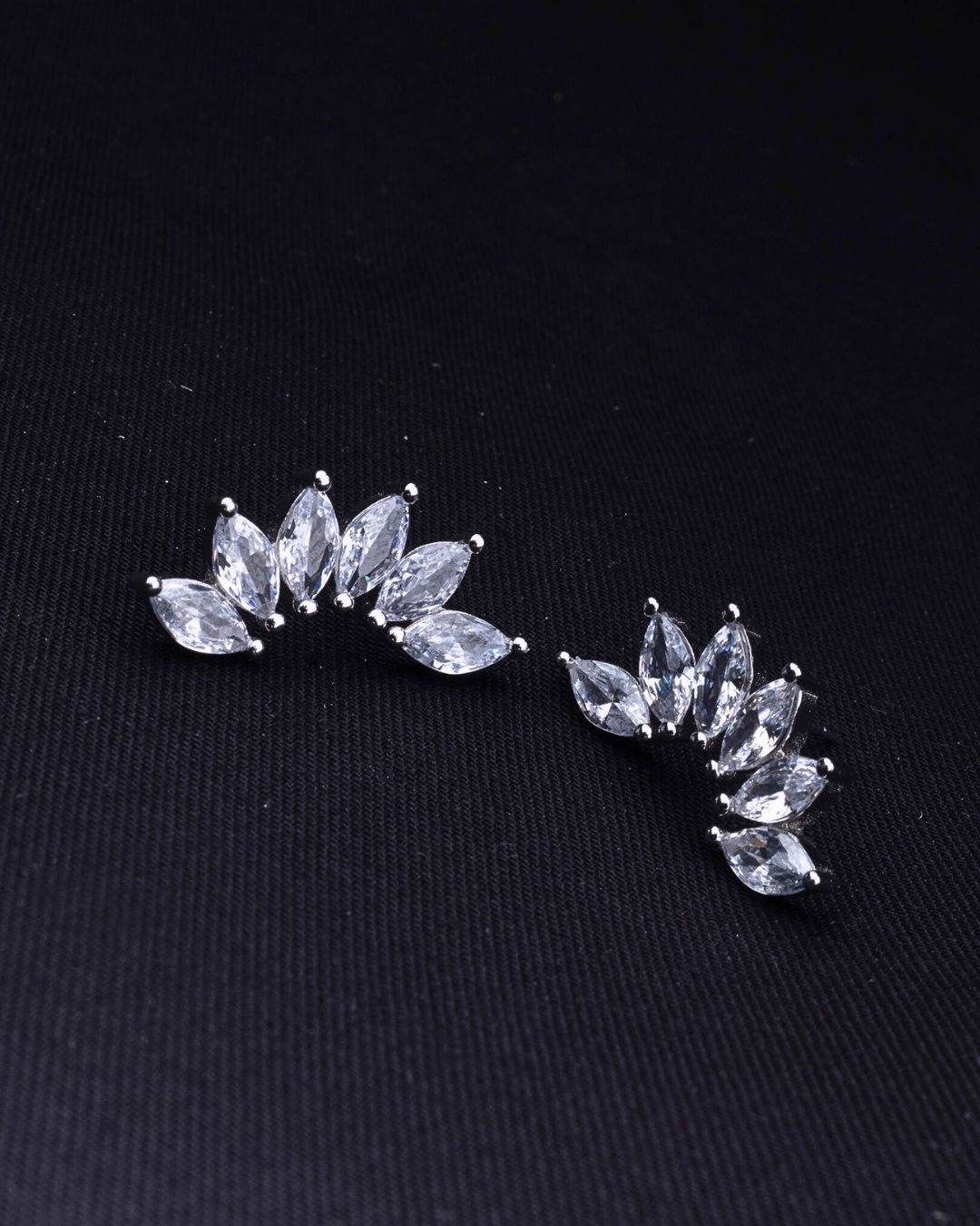 Pair of silver leaf-shaped earrings on a black background